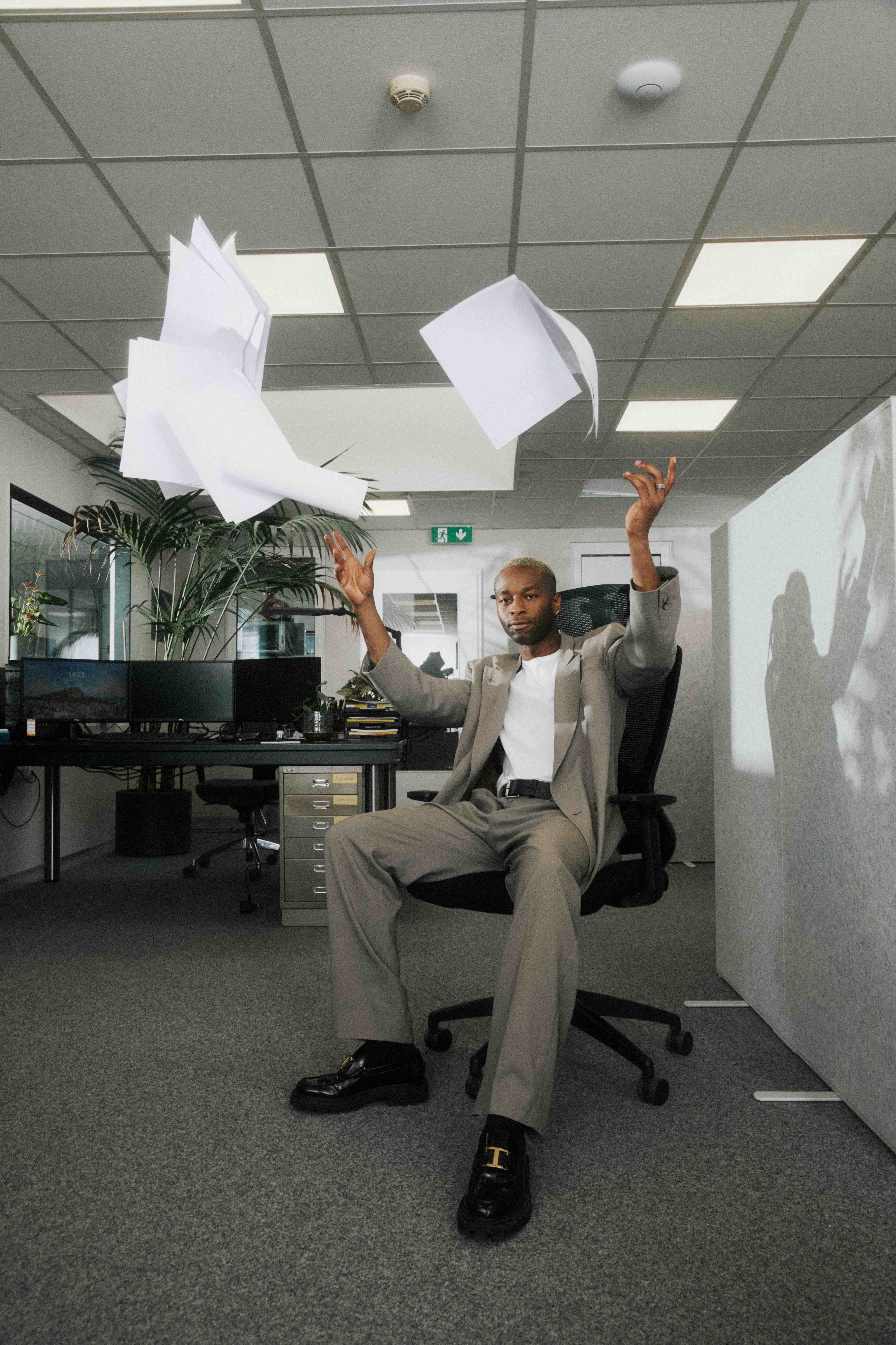 Person reclined in an office chair tossing papers overhead, composed — The Ad Spend brand image